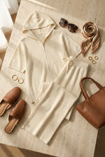 Completo composto da maglia a maniche corte con cappuccio e cerniera e pantaloni a gamba larga