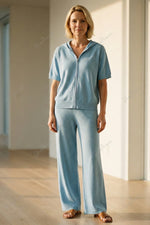 Completo composto da maglia a maniche corte con cappuccio e cerniera e pantaloni a gamba larga