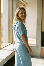 Completo composto da maglia a maniche corte con cappuccio e cerniera e pantaloni a gamba larga