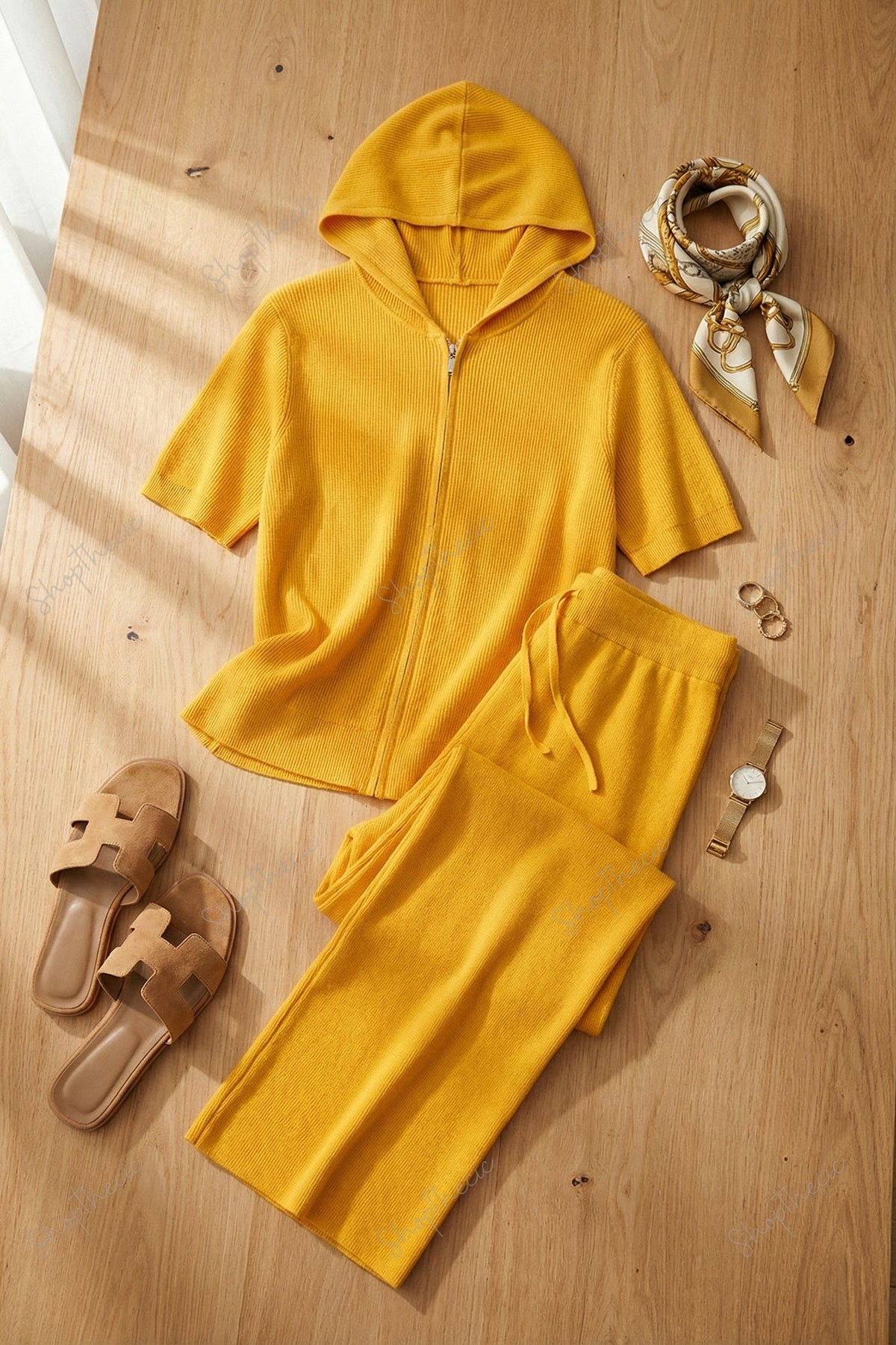 Completo composto da maglia a maniche corte con cappuccio e cerniera e pantaloni a gamba larga