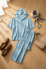 Completo composto da maglia a maniche corte con cappuccio e cerniera e pantaloni a gamba larga